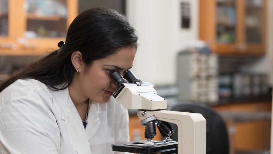 female looking into microscope